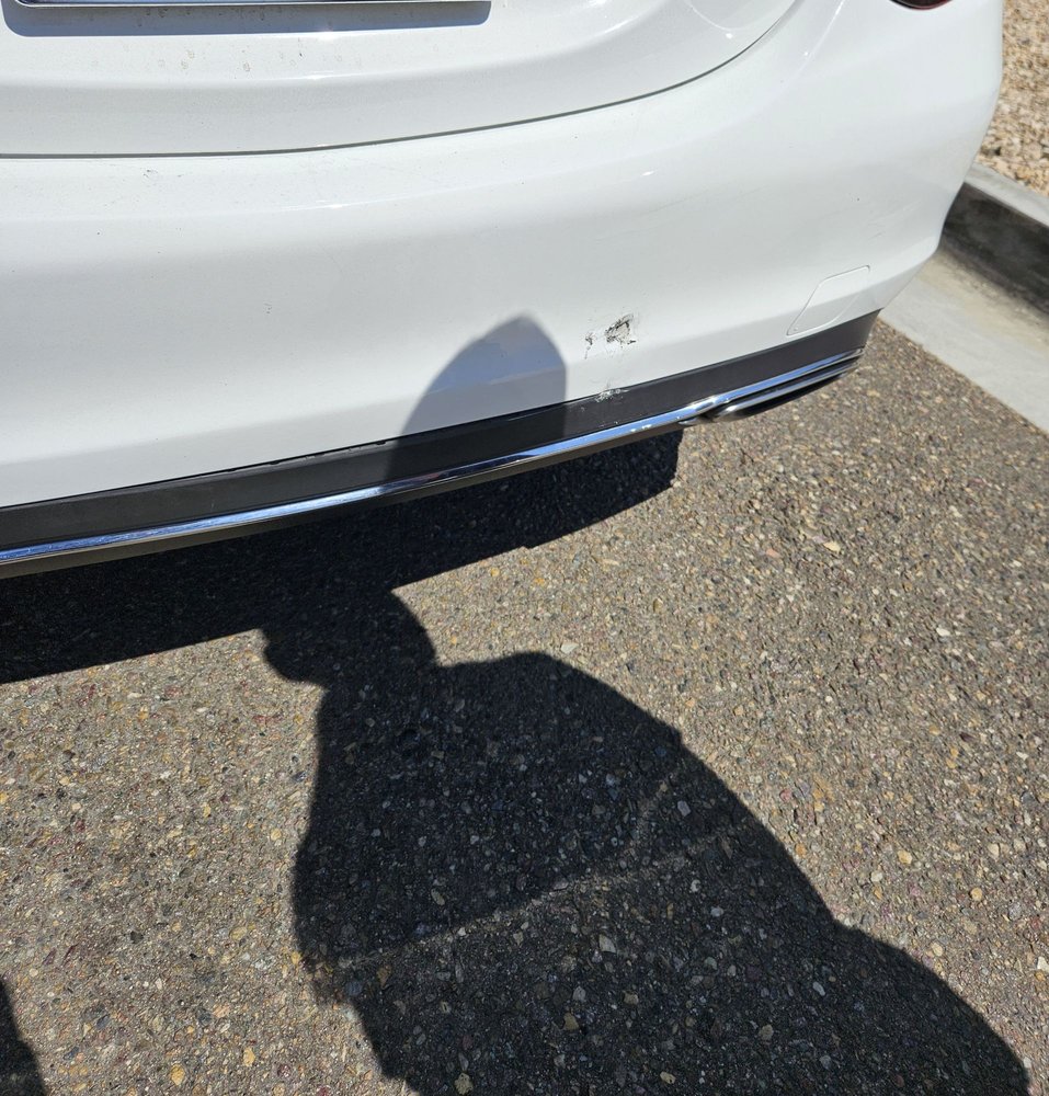 White vehicle rear bumper with scuff damage before repair